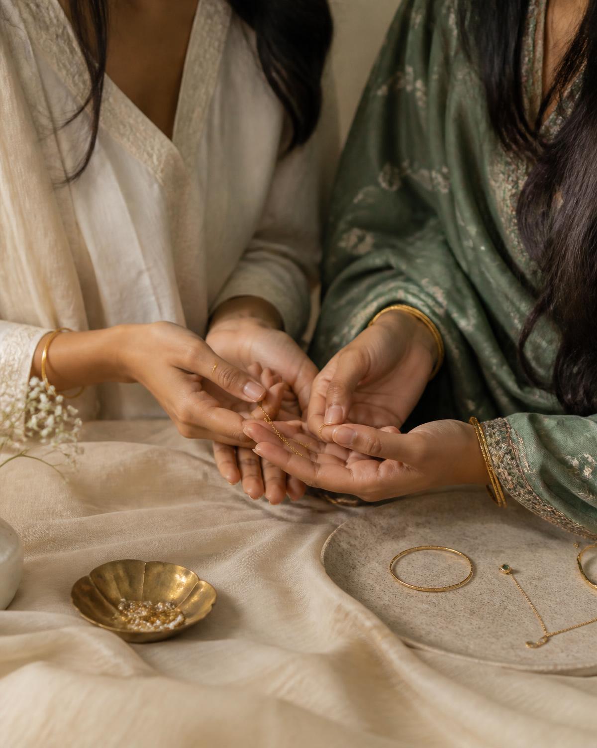 Paridhi and Jiya Bansal holding delicate gold jewellery over cream linen